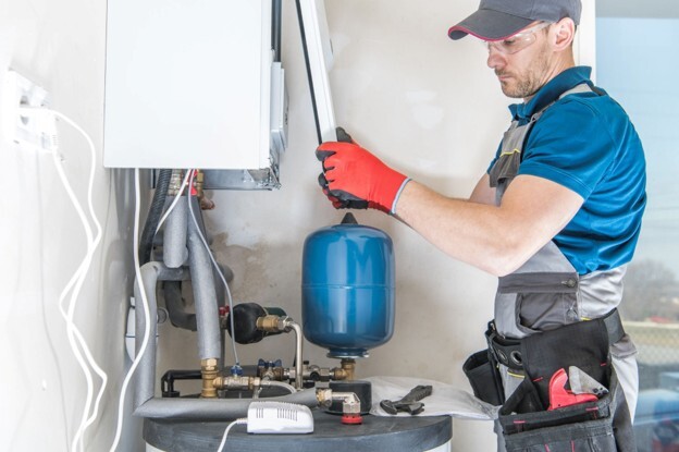 Heating engineer working on a boiler system, representing the cost of a boiler replacement for homeowners.