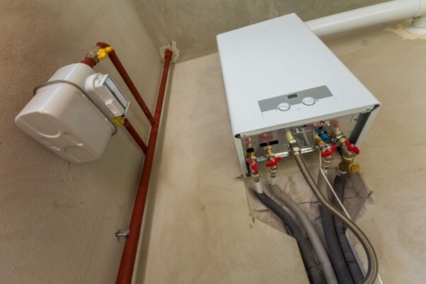 Preparing heating system for winter, with a wall-mounted domestic boiler, heating pipes and connections ready for seasonal maintenance.
