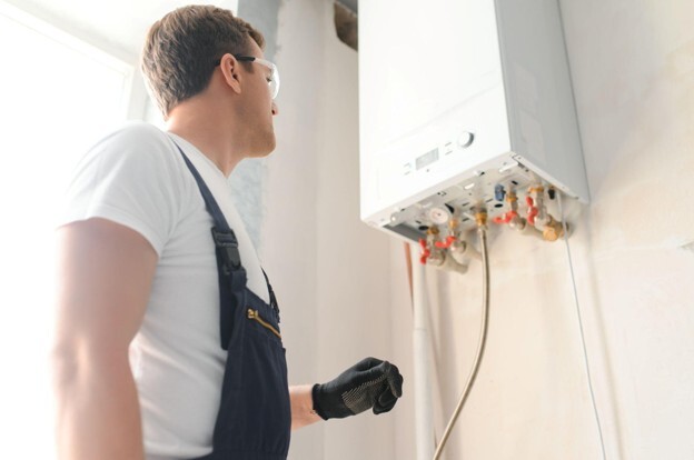 Heating engineer carrying out a full boiler service and inspecting a wall-mounted boiler in a home.