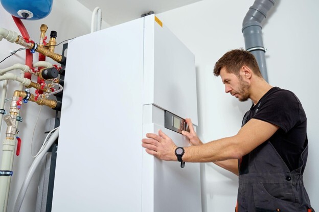 Heating engineer inspecting a system boiler and its controls in a residential property.